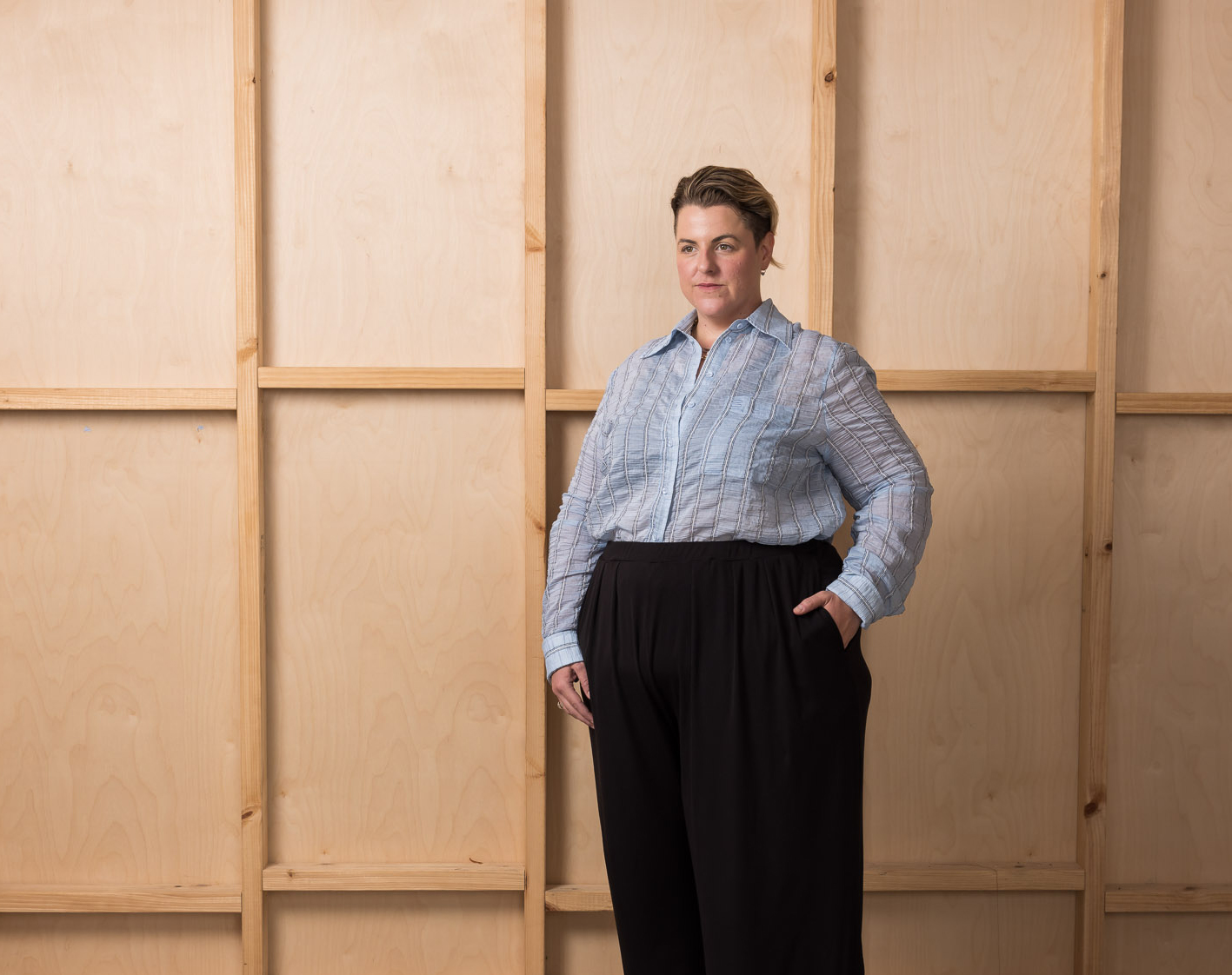 Person standing against a wooden backdrop