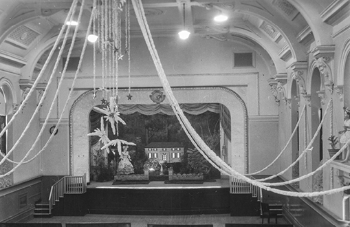 Historical black and white image of large chandelier and stage