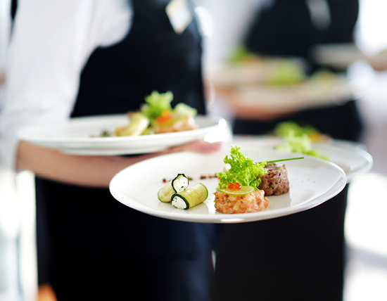 close up image of waiter holding two plates of fine dining food
