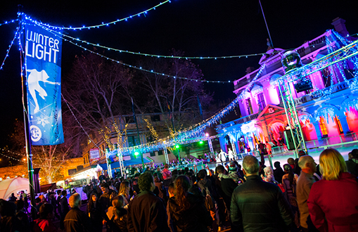 Image of the town hall lit up in colourful lights during the winter light festival, with crowds of people in front