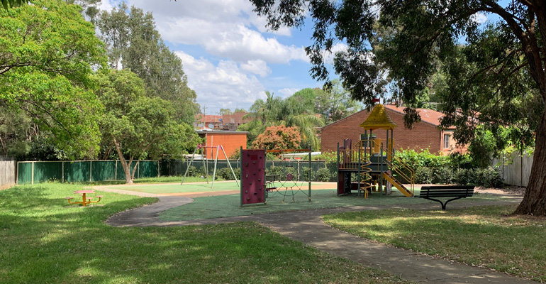 Park with play equipment including spider's net, swings, stairs and fireman's pole 