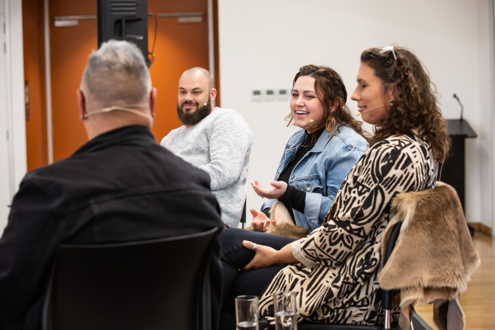 Four people sitting in a circle smile and talk