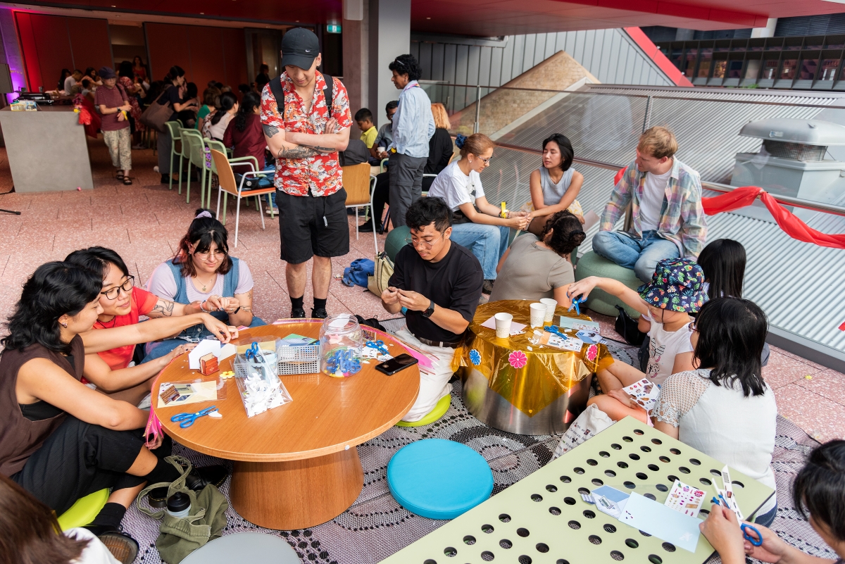 Group of people sitting at round wooden table and sitting on the floor