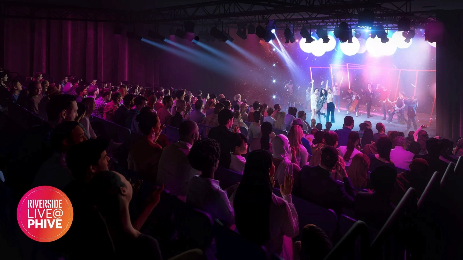 Audience watches a vibrant stage performance with colorful lights and energetic atmosphere. Performers are illuminated under bright spotlights.