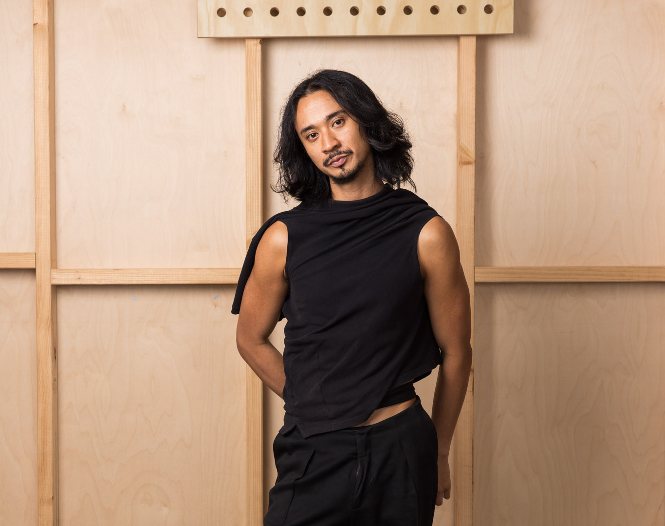 Person standing against a wooden backdrop