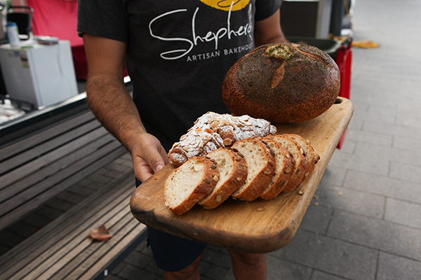 Sliced sourdough with pumpkin seeds, almond croissant and sourdough cob on wooden board