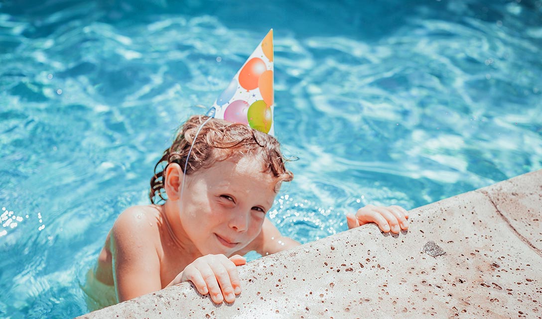 Child in the pool with party hat