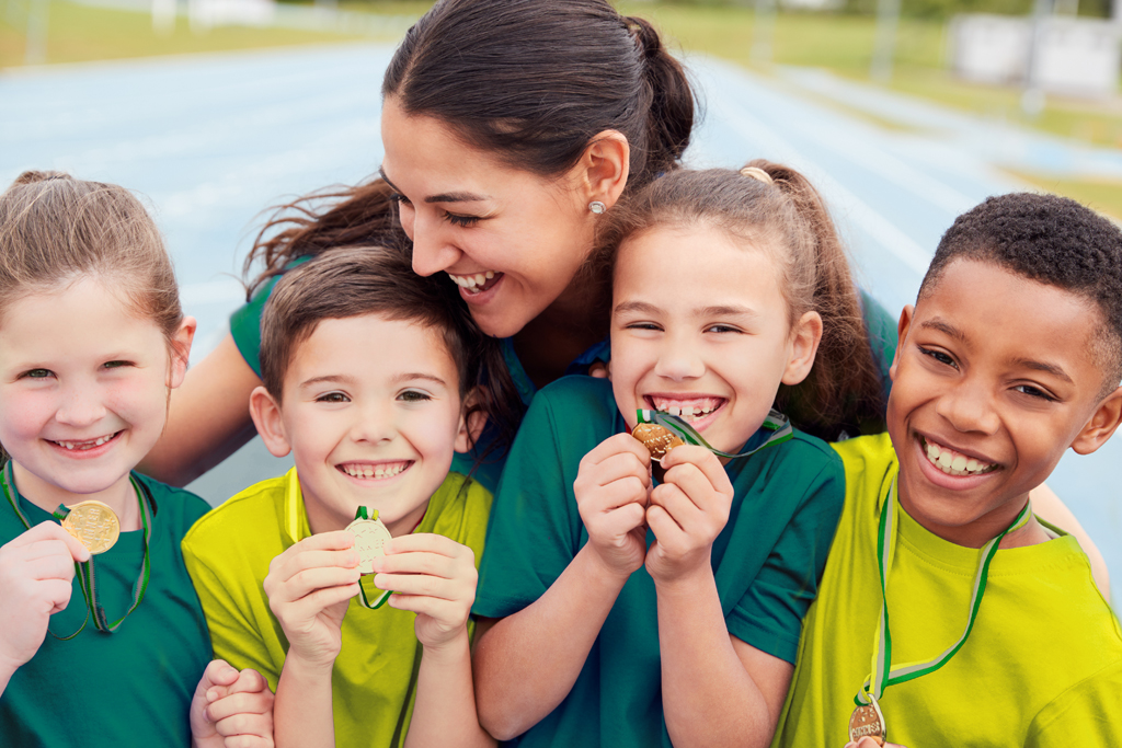 Children smiling and laughing holding medals 