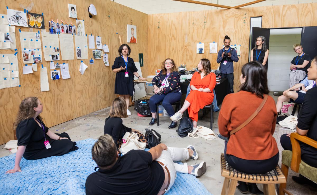 Image of artists and visitors grouped and talking inside a wood panelled studio