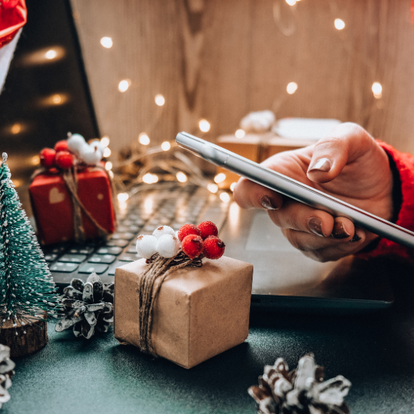 Hand holding mobile device with Christmas decorations in the background