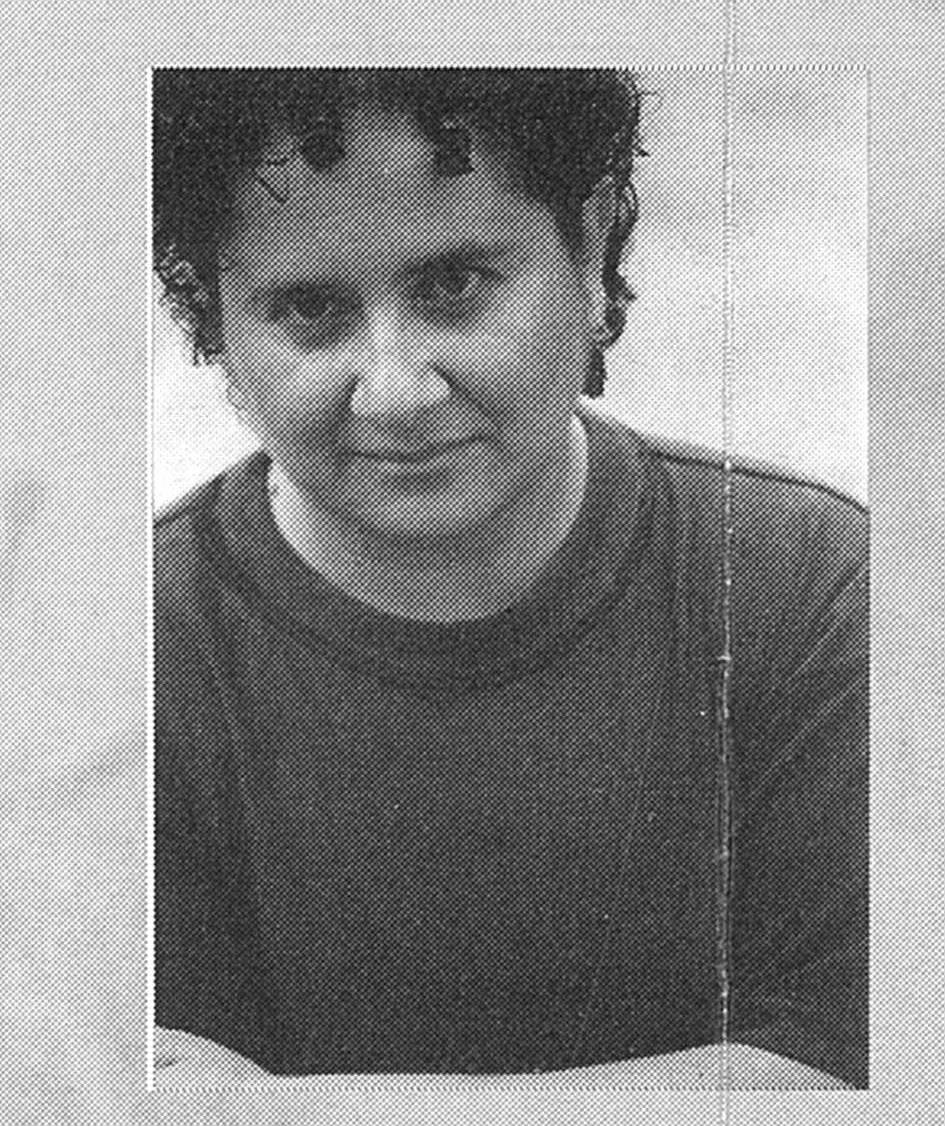 Black and white portrait of a person with short curly hair, wearing a dark T-shirt. The image has a textured, worn effect. The expression is calm.