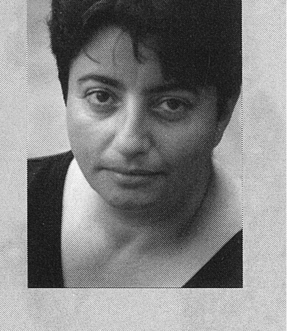 Black and white portrait of a person with short dark hair, looking directly into the camera with a neutral expression. The image has a textured, grainy effect.