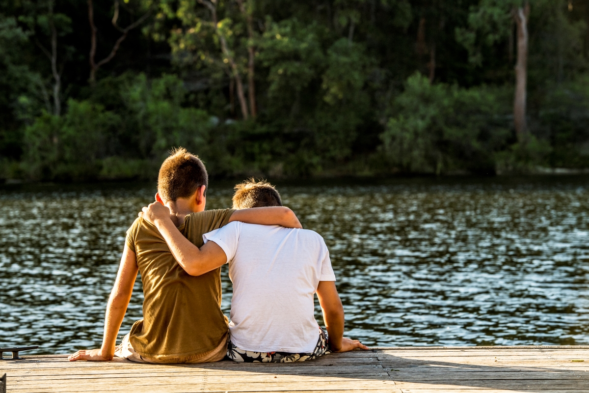 Two boys with arms around each other at Lake Parramatta