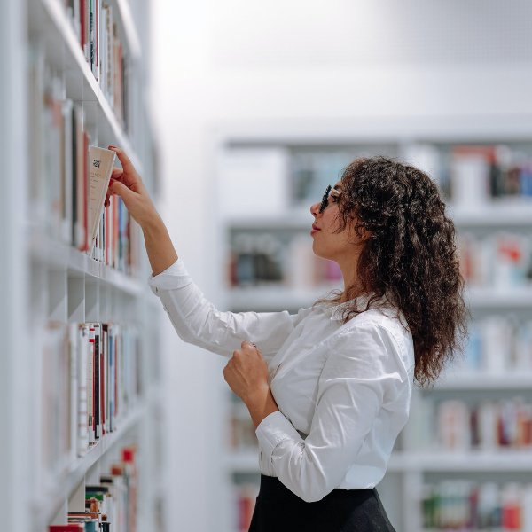 Woman taking out a book from a shelf in library