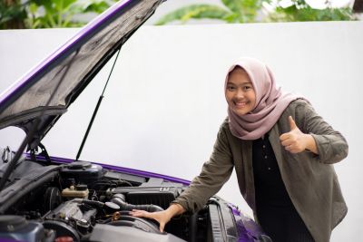 Women with thumbs up working on car