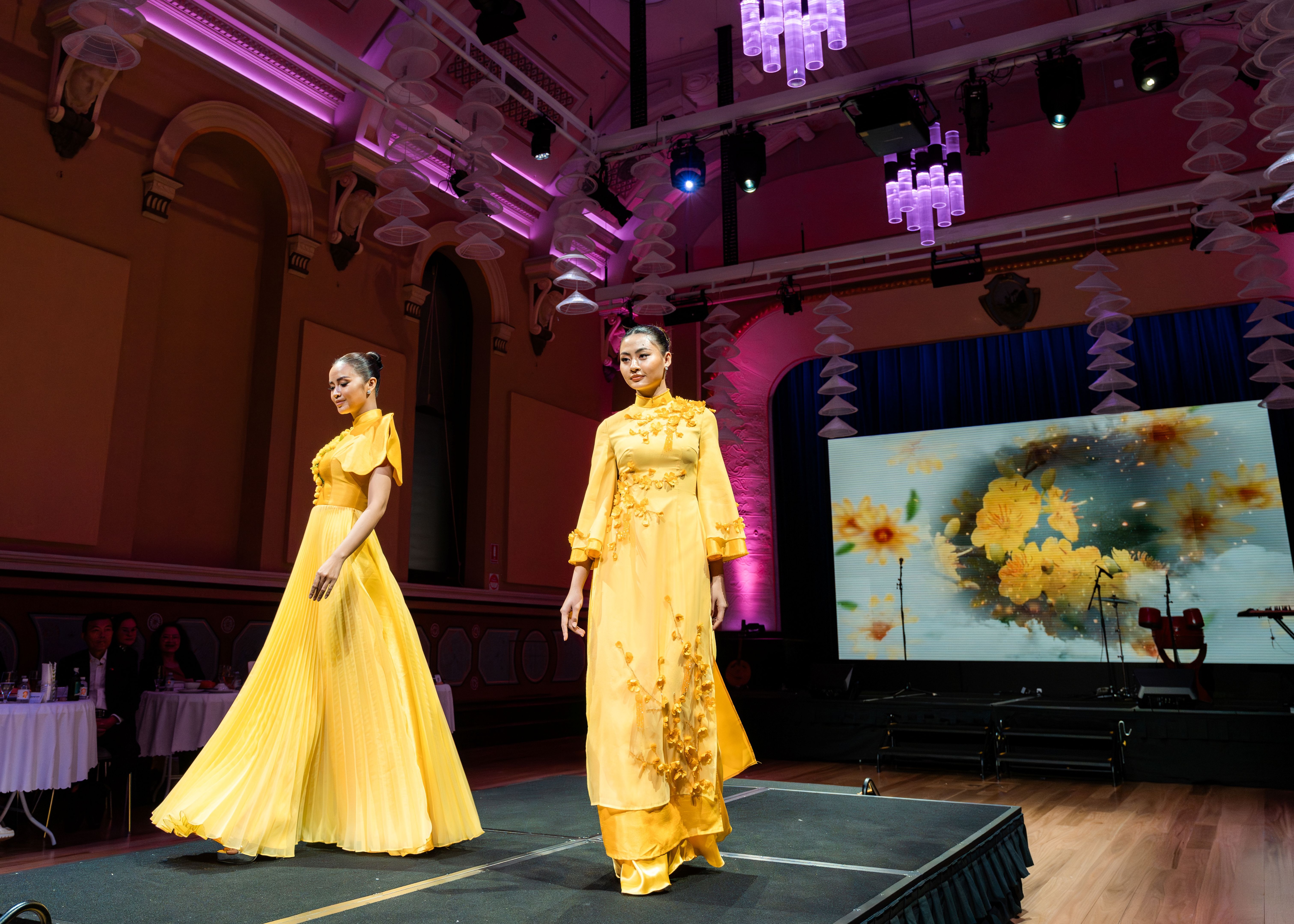 Two models on the catwalk wearing yellow dresses