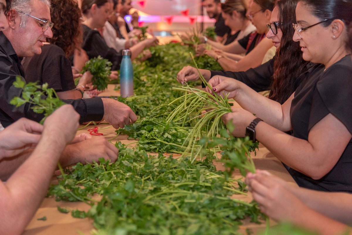 Group of people sitting at table picking parsley leaves