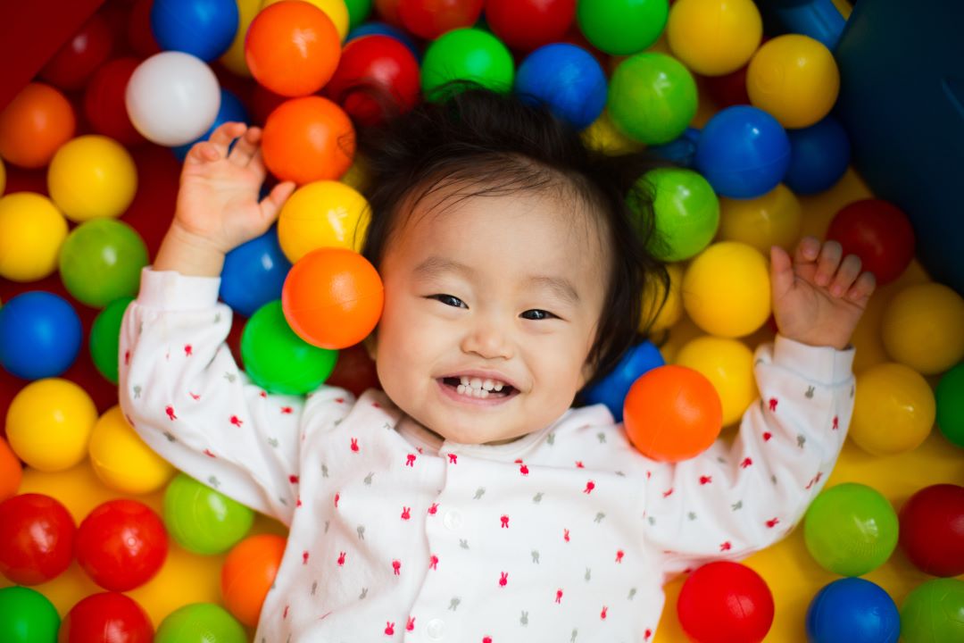 Asian baby smiling in ball pit